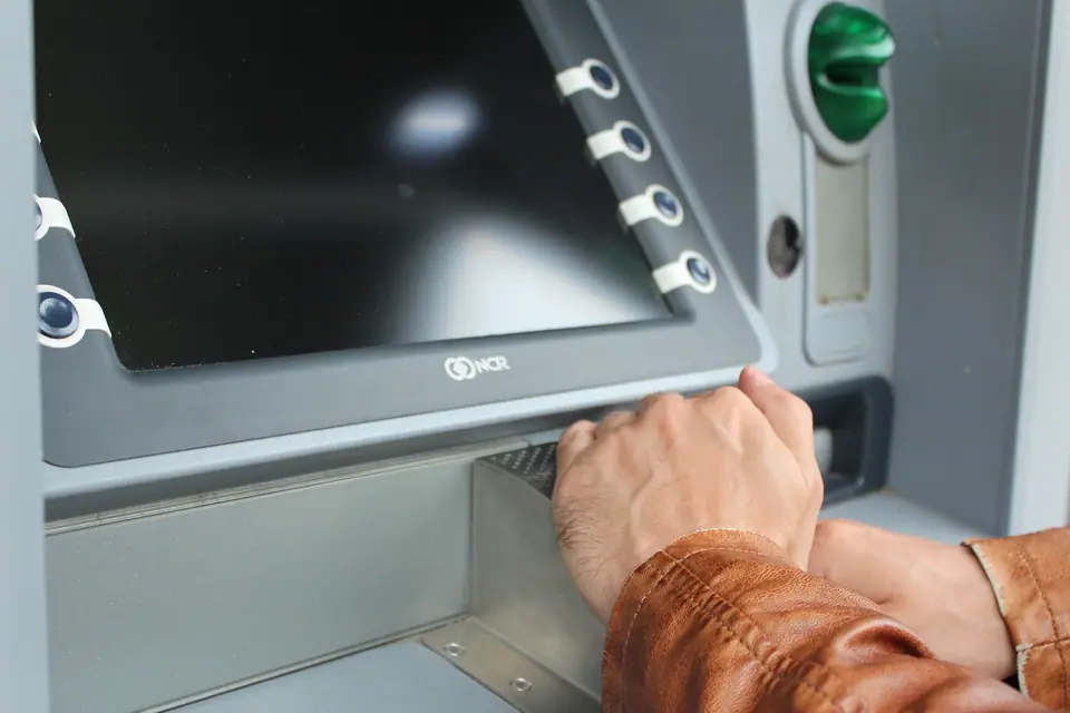 Bir ATM’nin ekranı ve para çekme bölmesine uzanan el