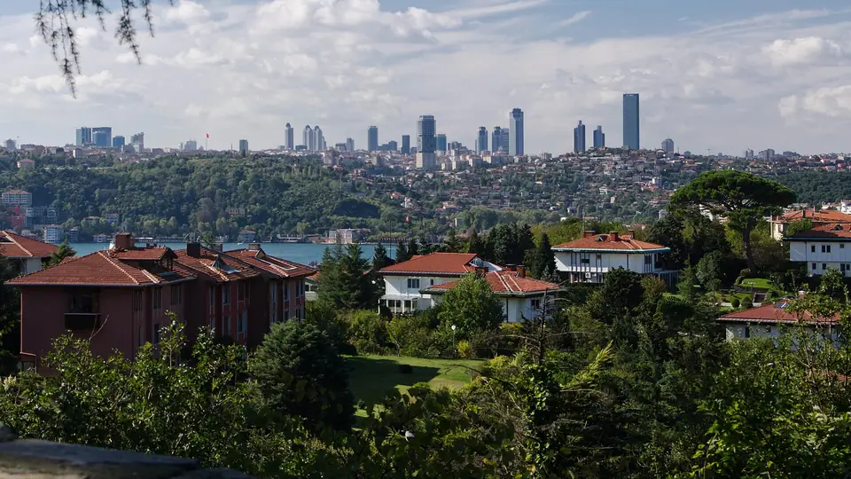 İstanbul Boğazı kıyısında kırmızı çatılı evler ve uzakta gökdelenler