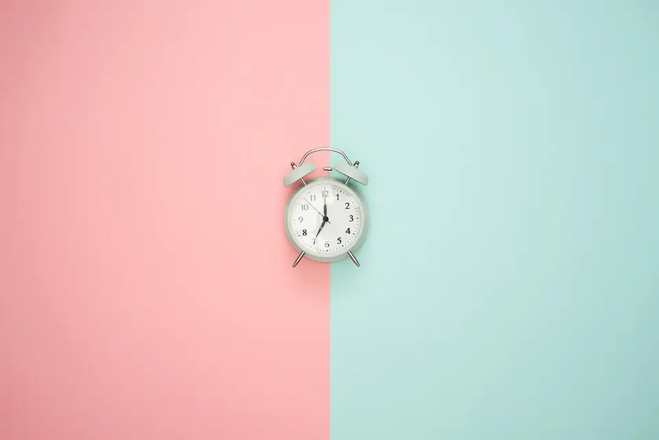 Pembe ve açık yeşil iki renkli fonda küçük bir çalar saat