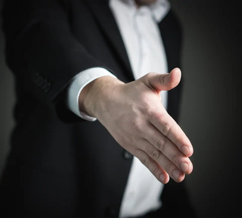 Takım elbiseli bir kişinin tokalaşmak için uzattığı el
