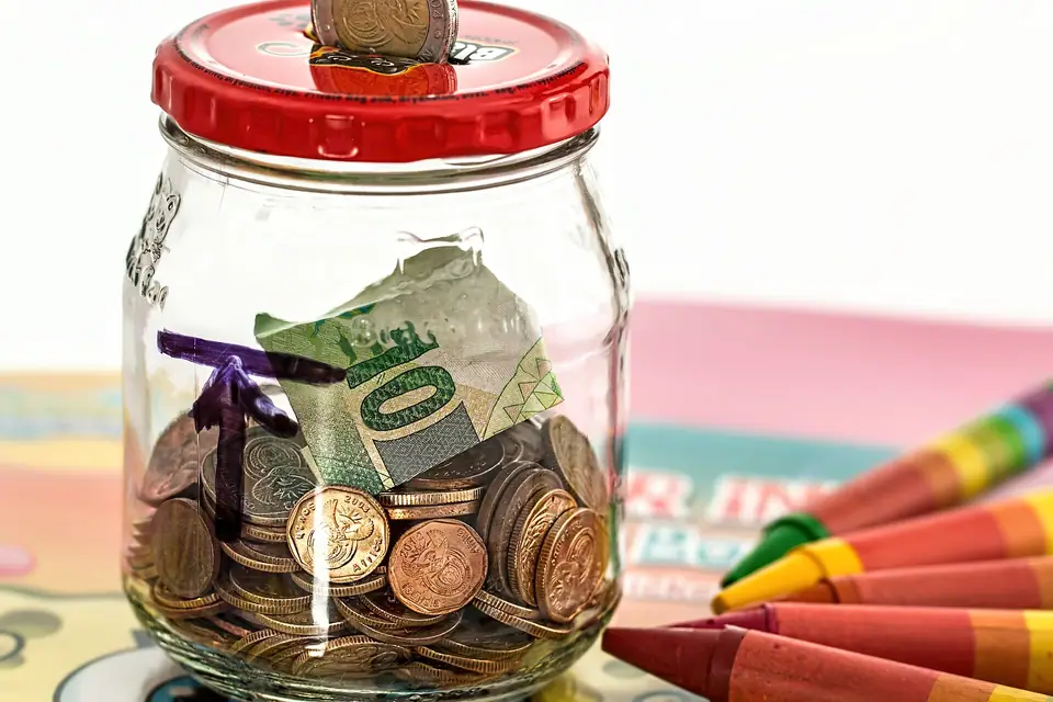 Bozuk para ve kâğıt paranın biriktirildiği cam kavanoz, yanında boya kalemleri