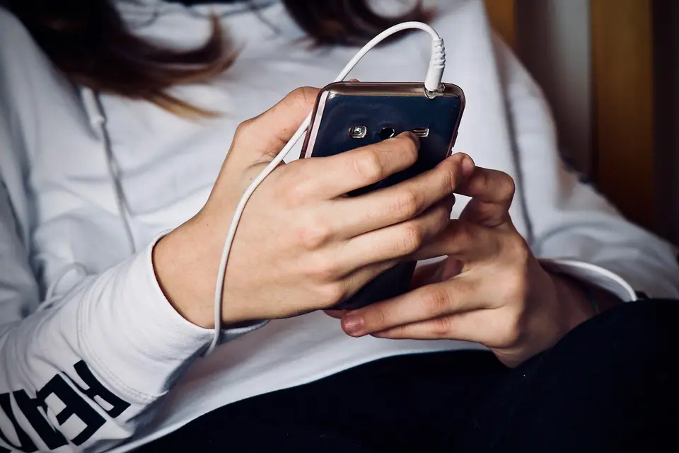 İki elle tutulan ve kulaklık kablosu takılı akıllı telefon