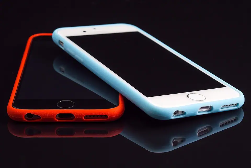 Koyu yüzeyde yan yana duran iki akıllı telefon